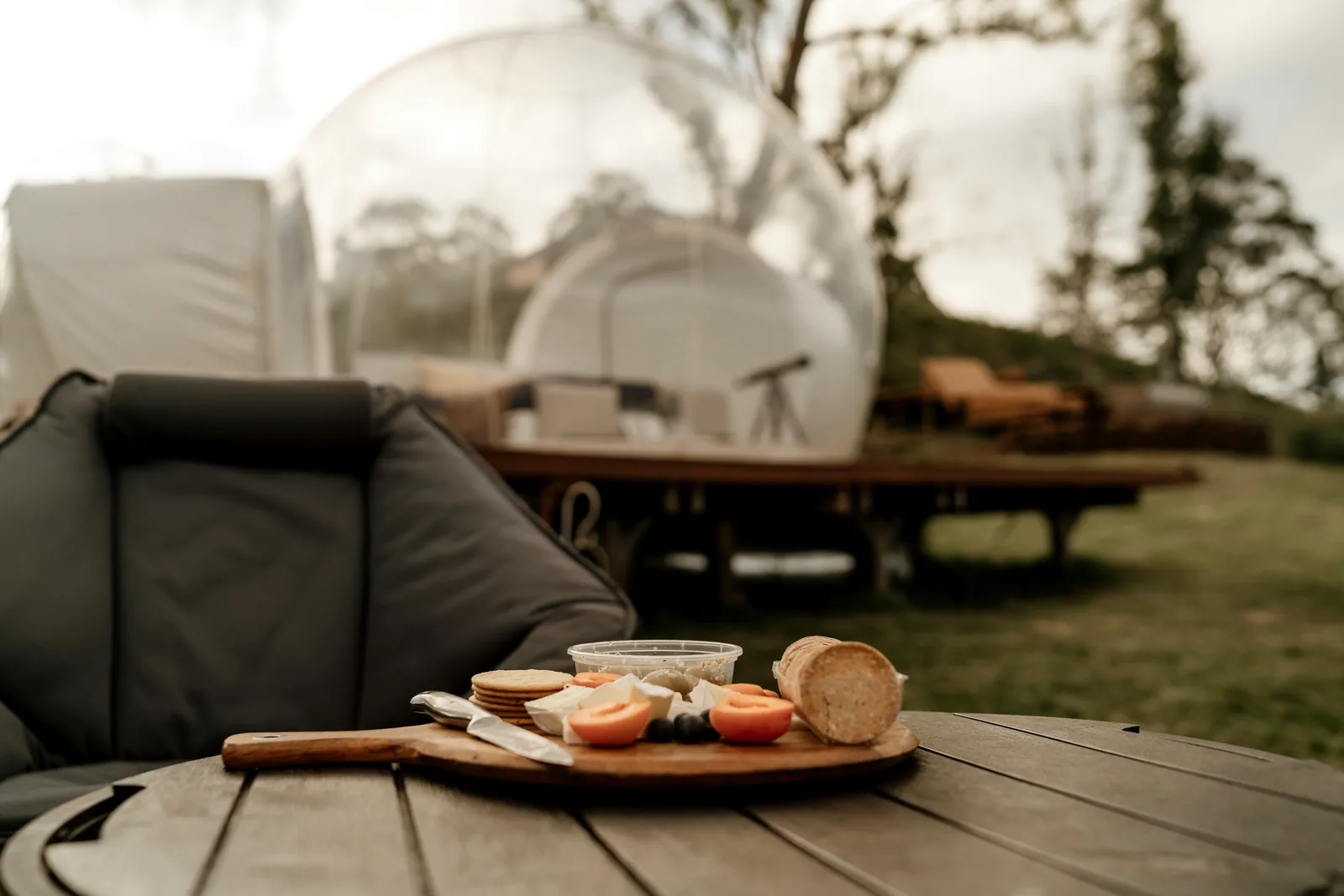 A grazing board on an outdoor table near a glamping dome