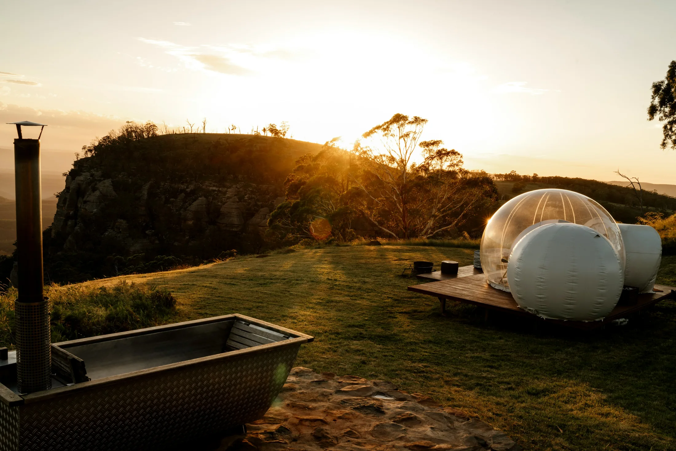 A Green Glow glamping dome and outdoor bath at sunset