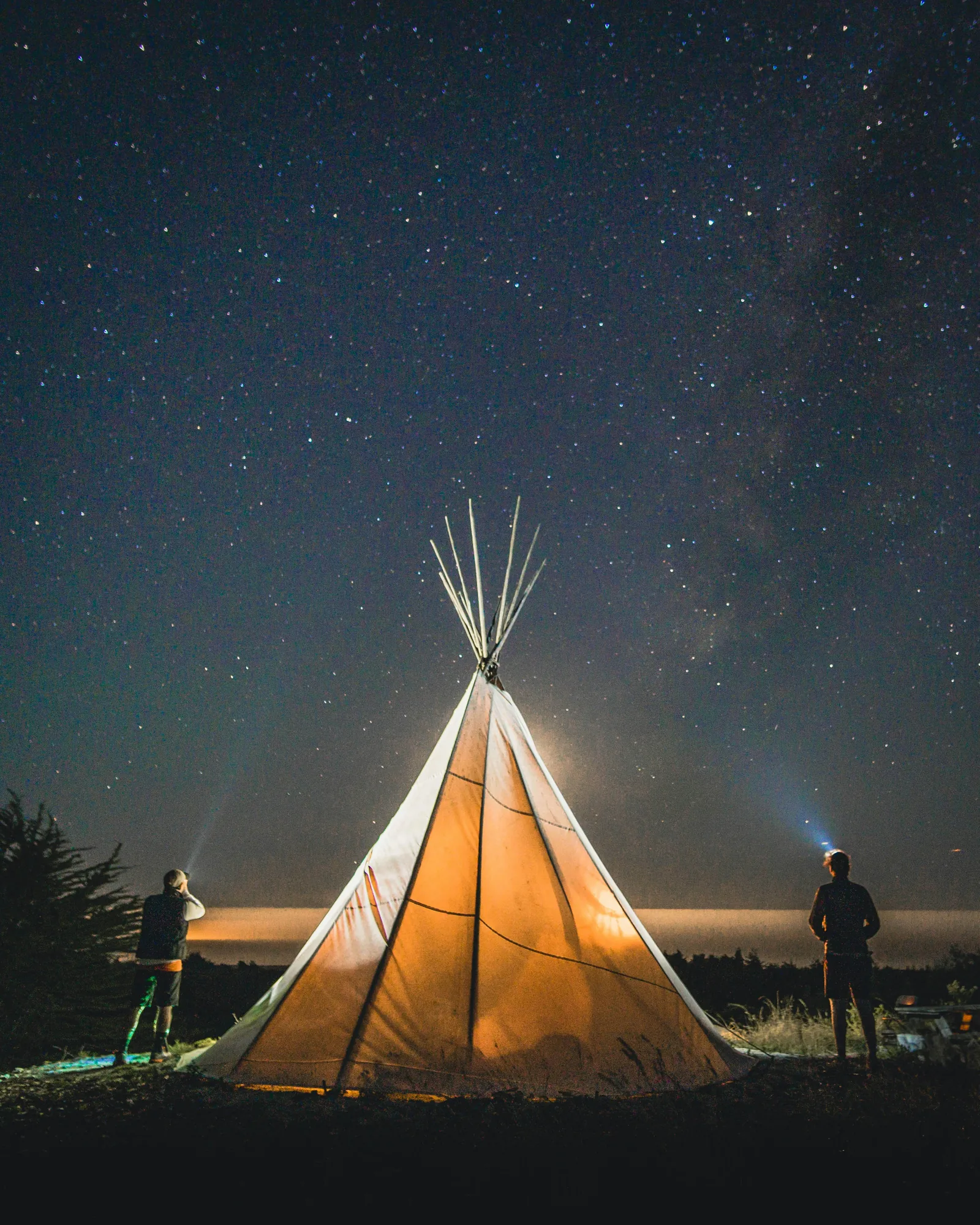 A glowing tent under a clear star-filled sky